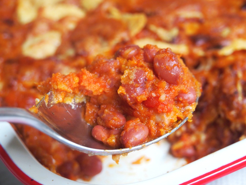 spoonful of mexican beans with cheesy taco topping