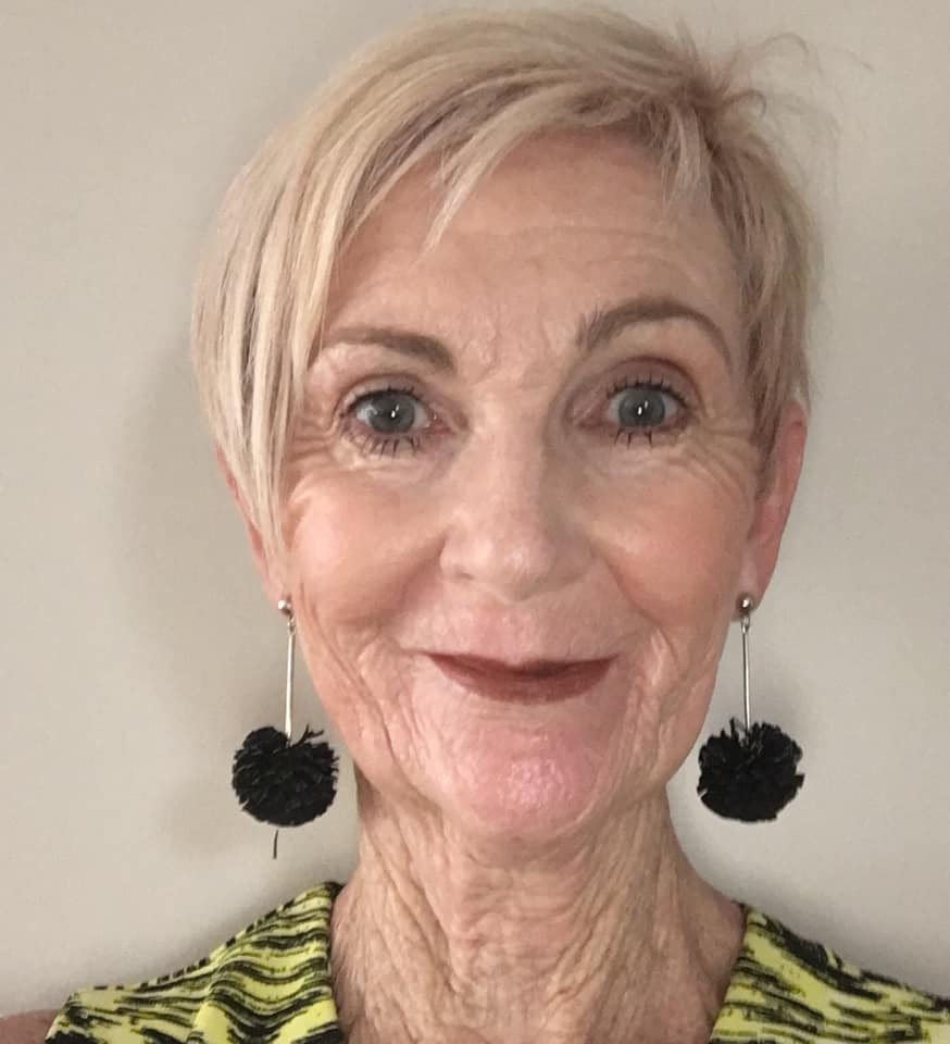 woman with short blonde hair wearing pom pom earrings