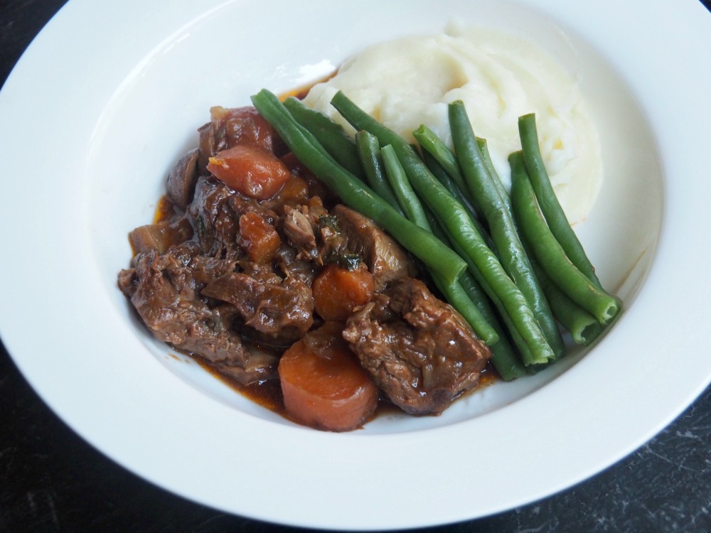 beef and ale stew with mash and green beans on a plate