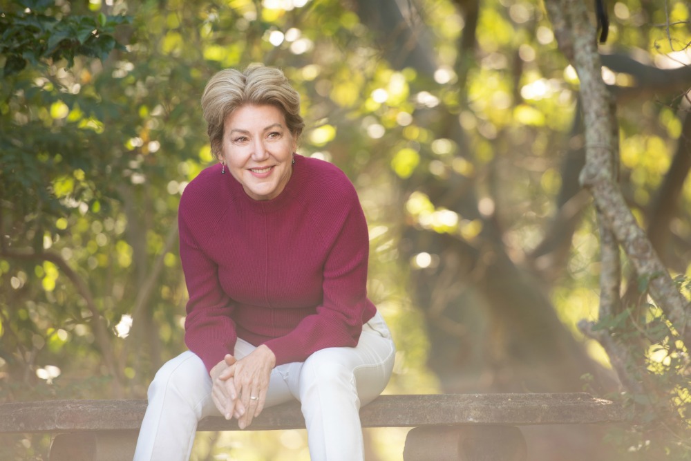 women sitting on a bench wearing burgandy jumper and white jeans