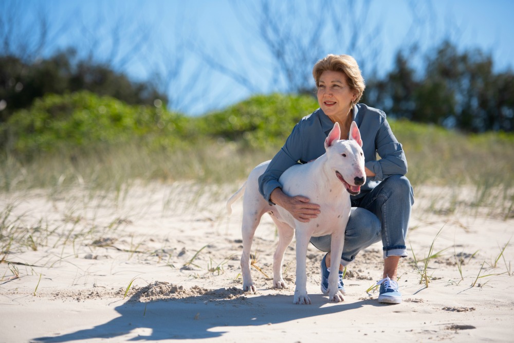 woman hugging her dog on the beach