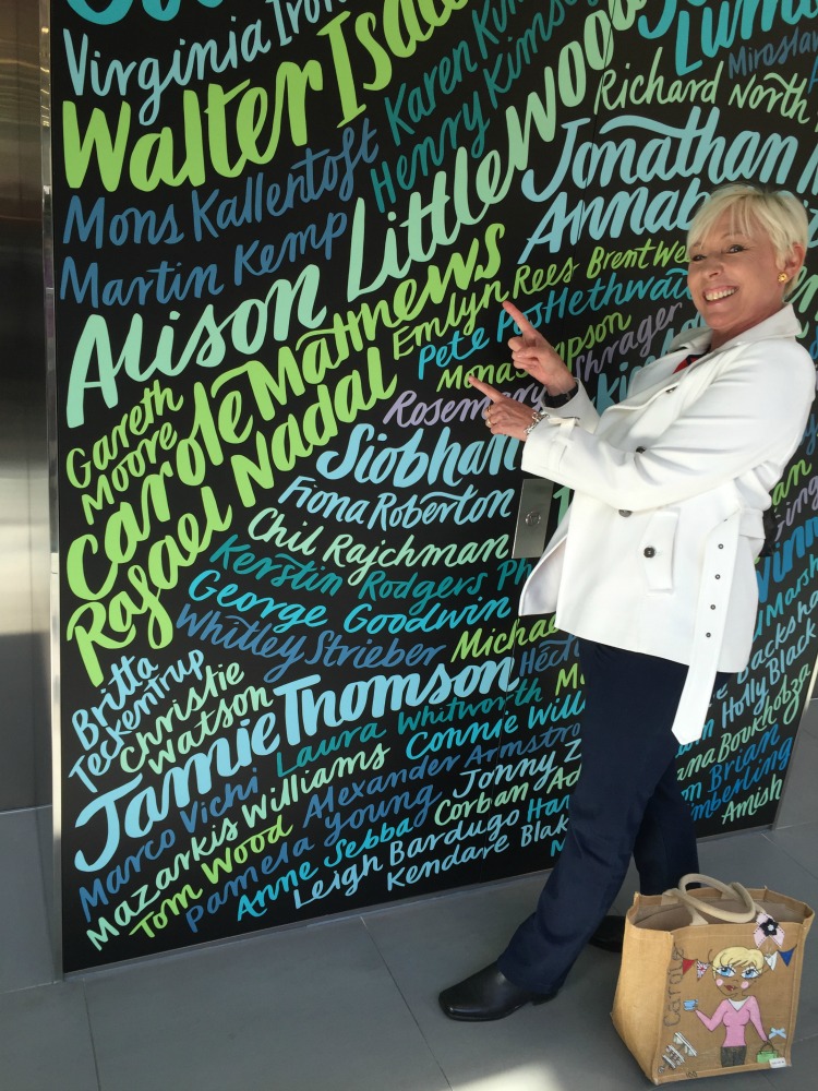 Carole Matthews author pointing at her name on a wall