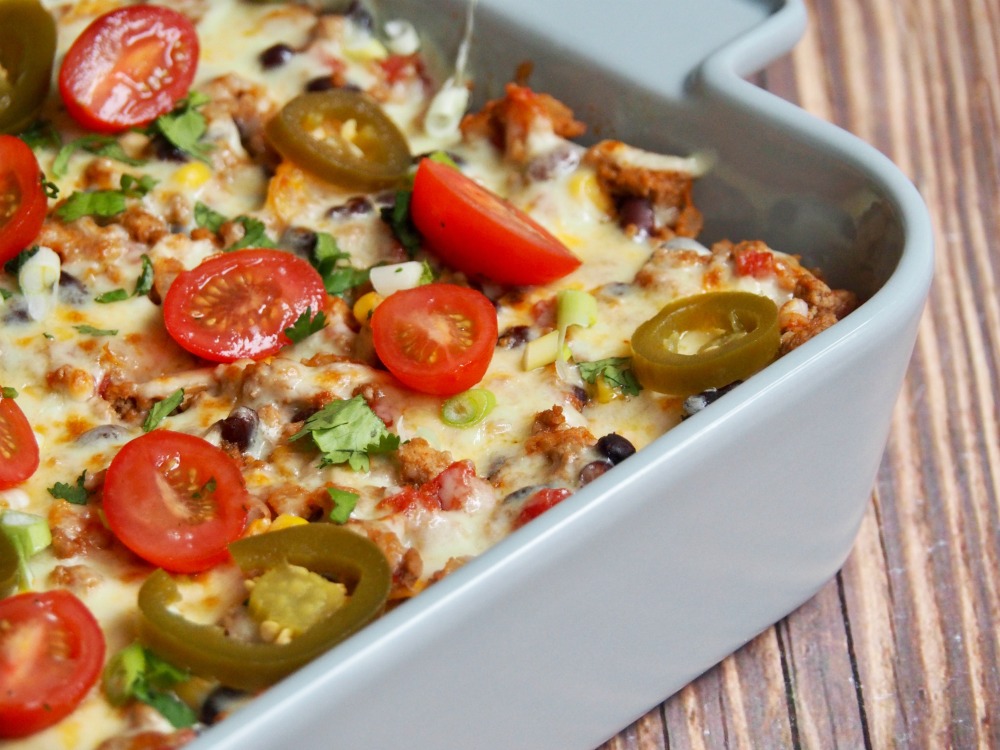 loaded turkey nachos topped with cheese coriander and cherry tomatoes