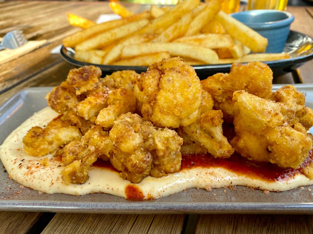 plate of fried cauliflower in front of a large portion of chips