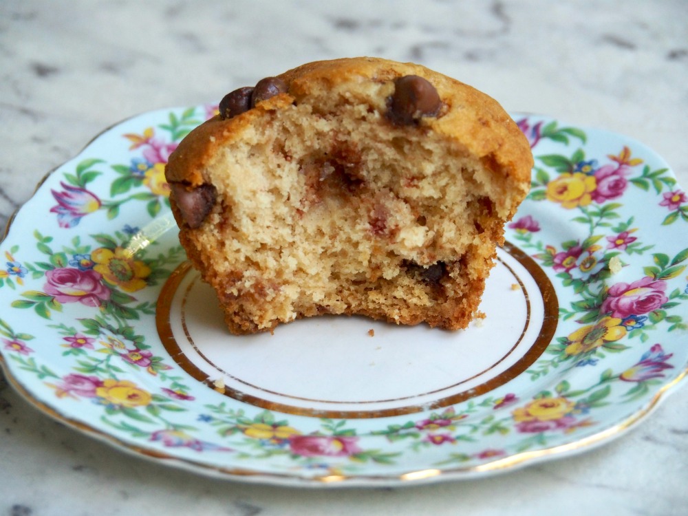 a bite taken out of a pear and choc chip muffin on vintage floral plate