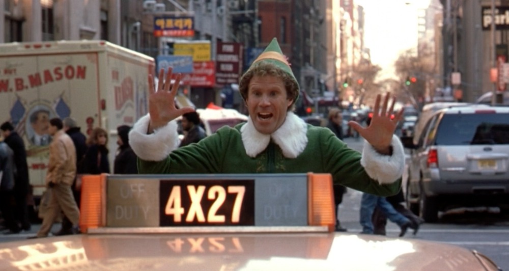 Will Ferrell as Elf standing in front of a NY taxi