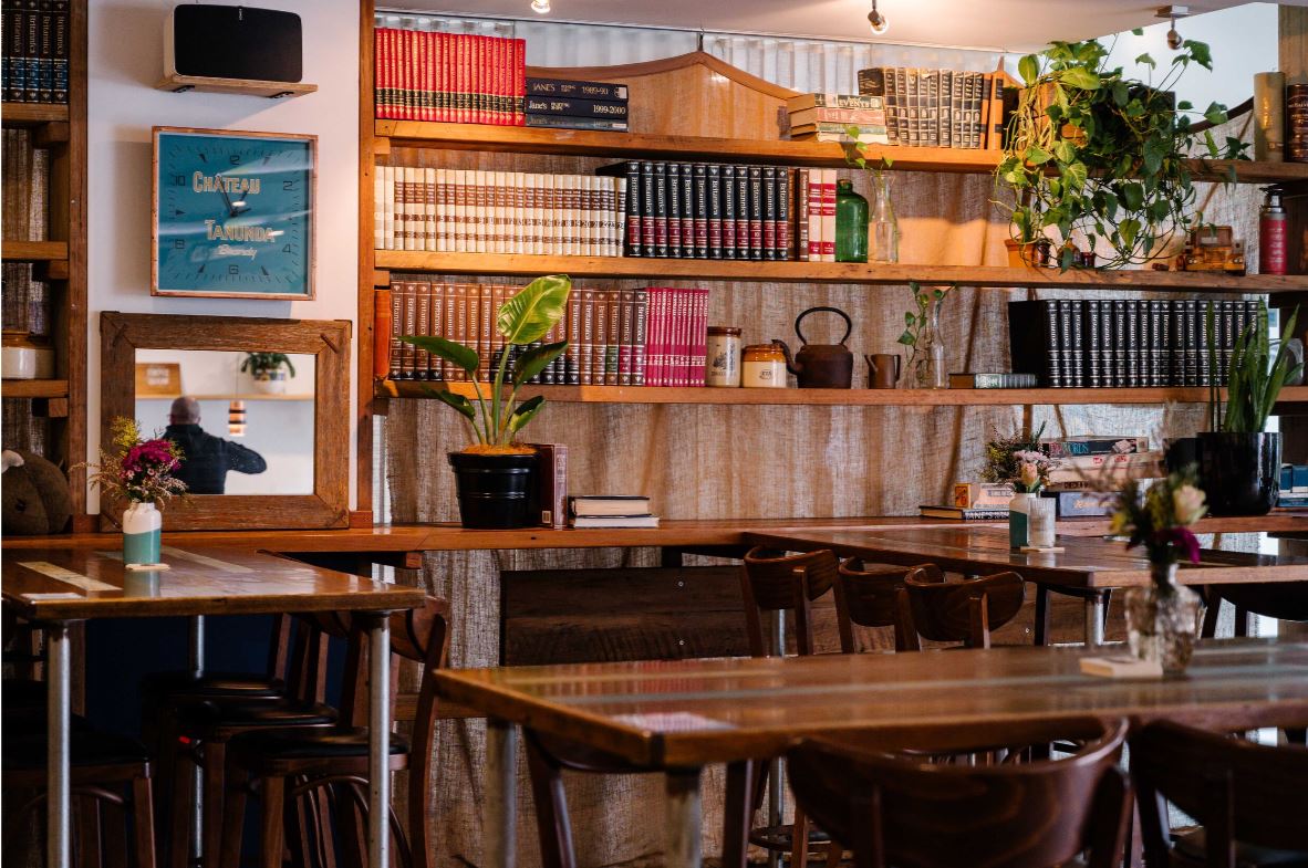 Book lined shelves and wooden tables in cosy bar