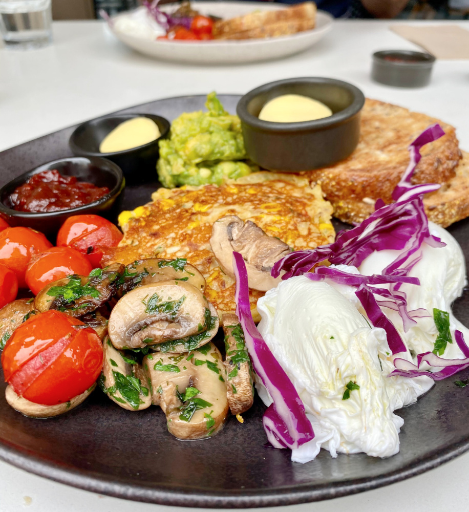 big vegetarian breakfast with poached eggs tomatoes mushrooms and corn fritter