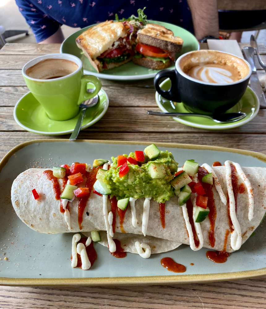 burrito topped with guac and coffee cup in background