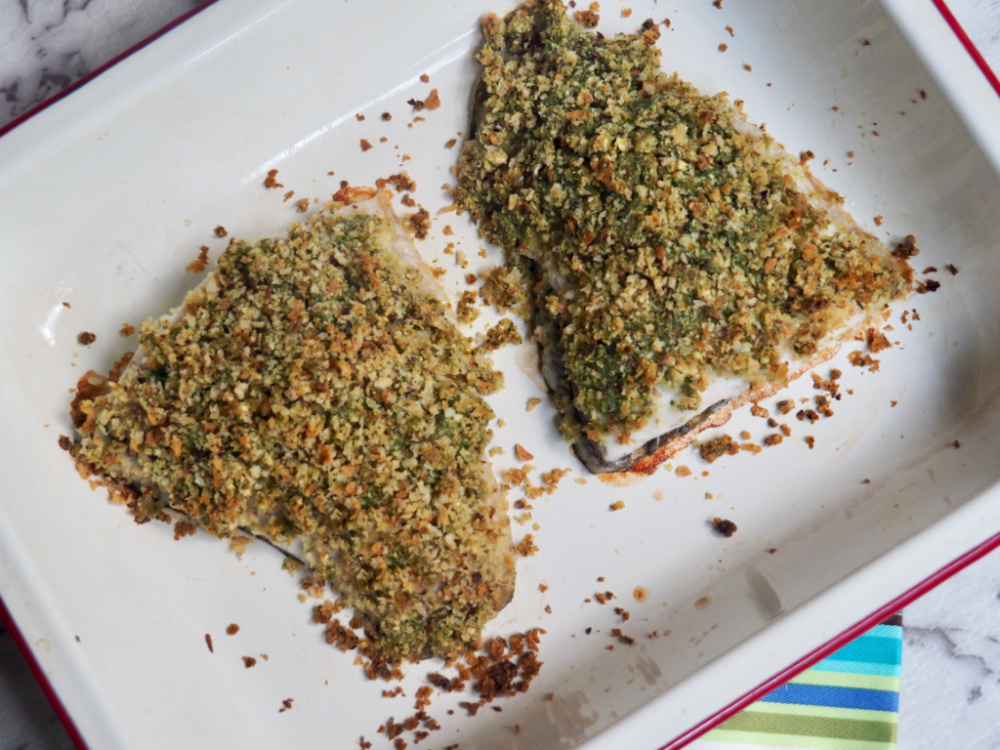 two fillets of pesto crumbed fish in baking dish