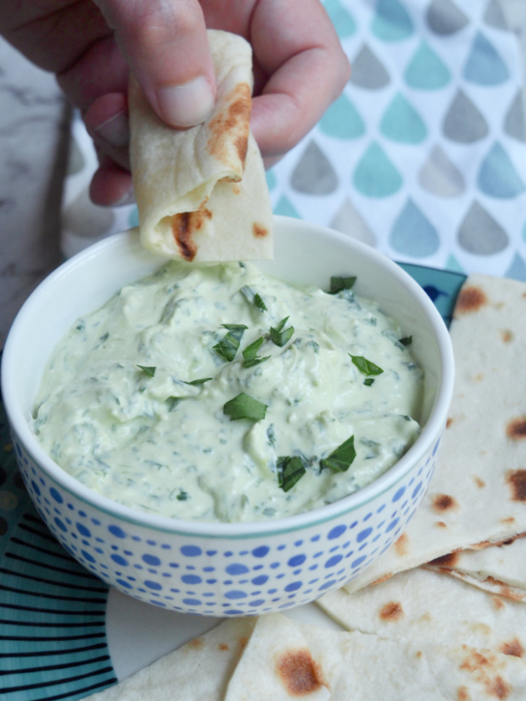 dipping bread into bowl of spinach and feta dip