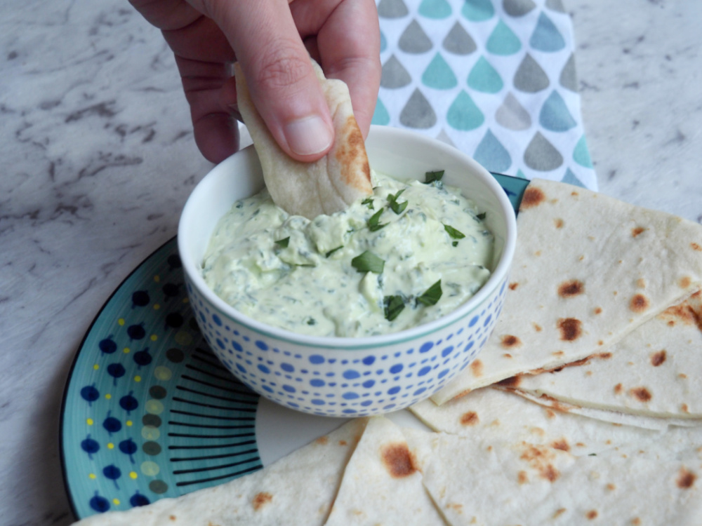 dipping bread into spinach and feta dip