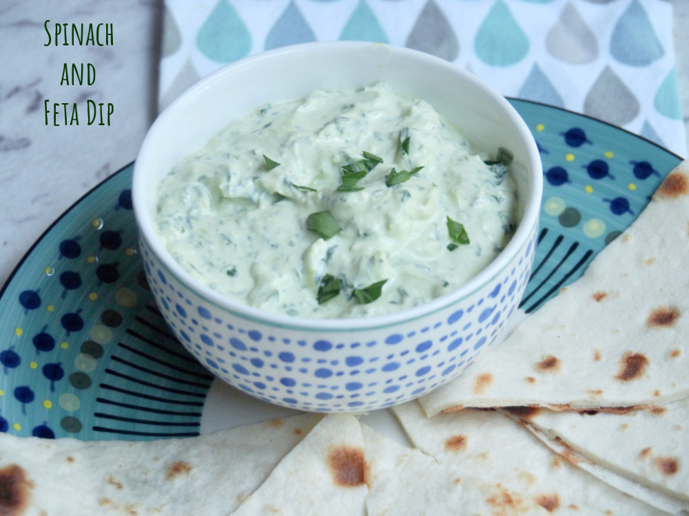 spinach and feta dip in small bowl on plate with flatbread