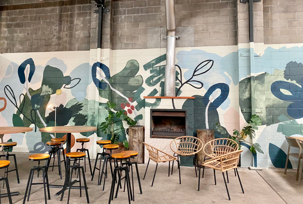 high chairs and table in industrial looking cafe with wall mural