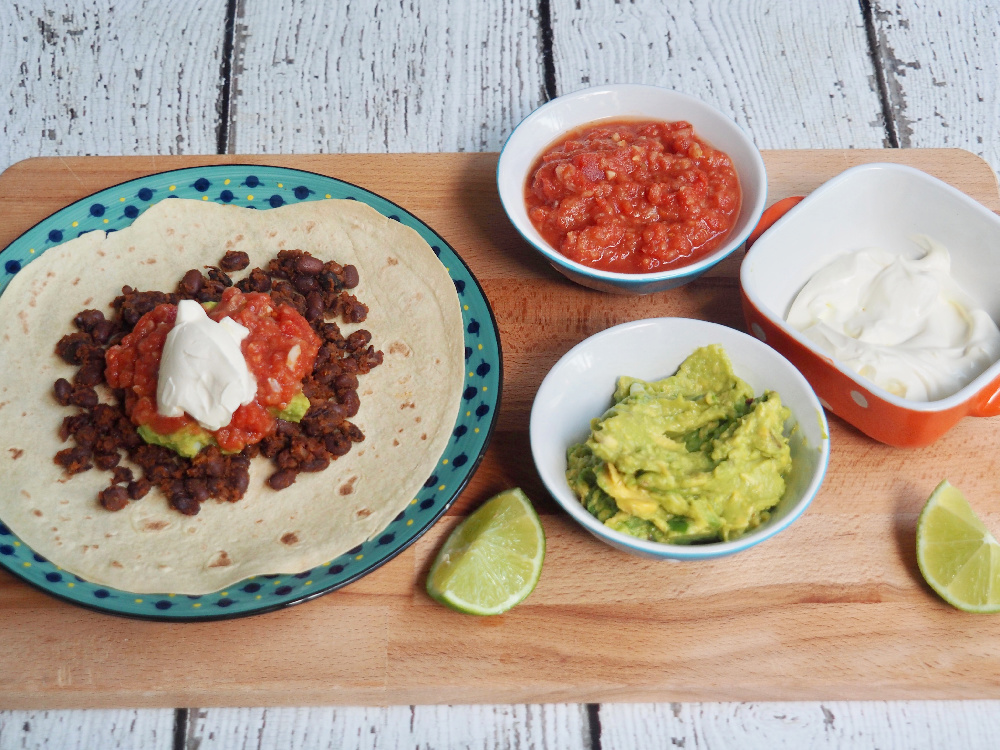 black bean chilli on tortilla with salsa guacamole and sour cream