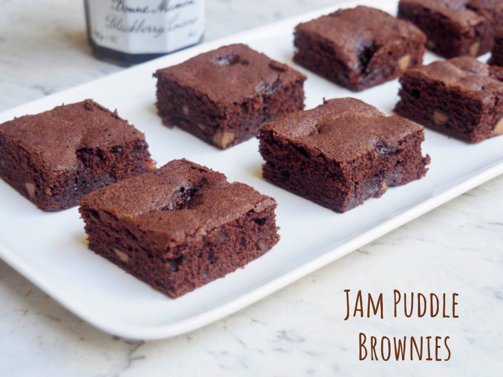 plate of jam puddle brownies with jam jar in background