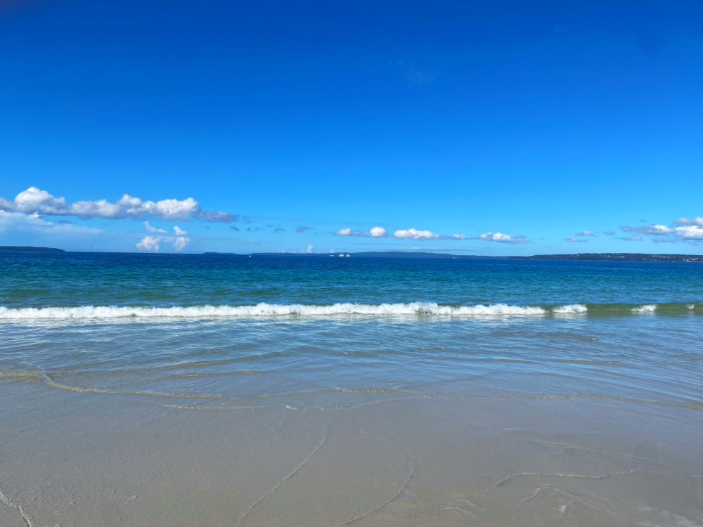 deep blue sky and waves crashing on to sand