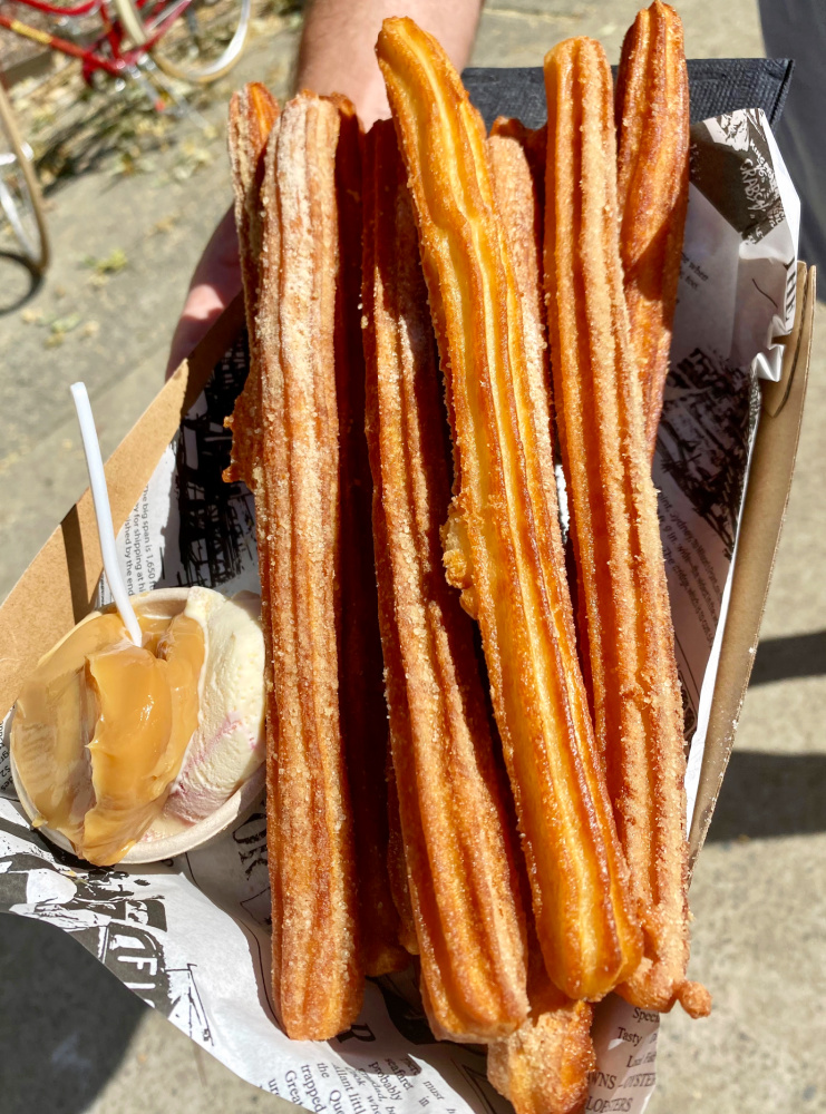 churros with caramel sauce and ice cream beach is in the background