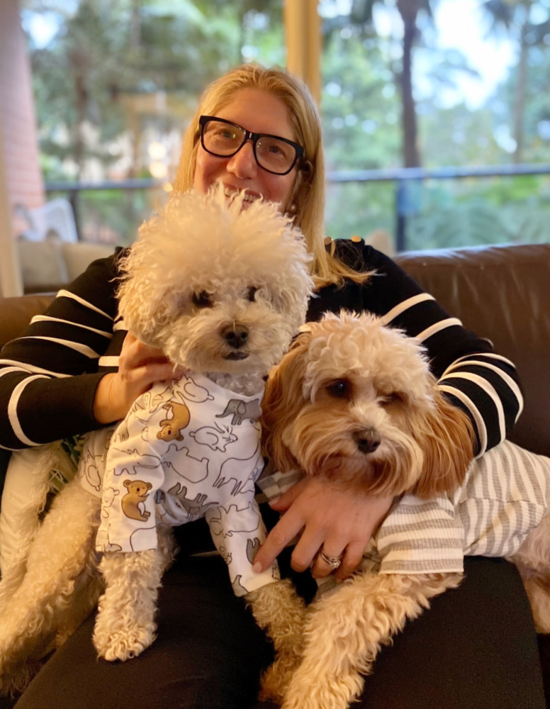 woman cuddling two oodle dogs