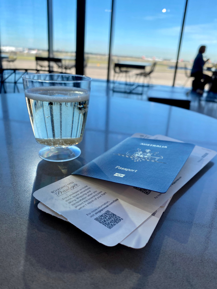 a passport boarding pass and glass of prosecco