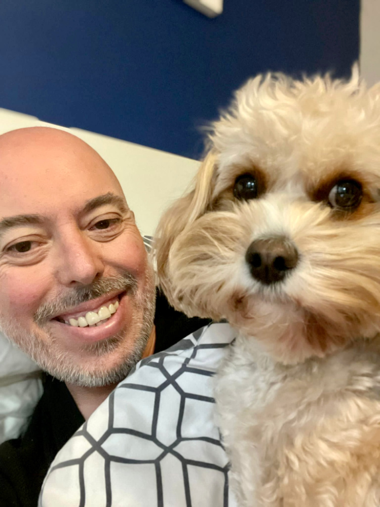 a man and his cavoodle lying in bed