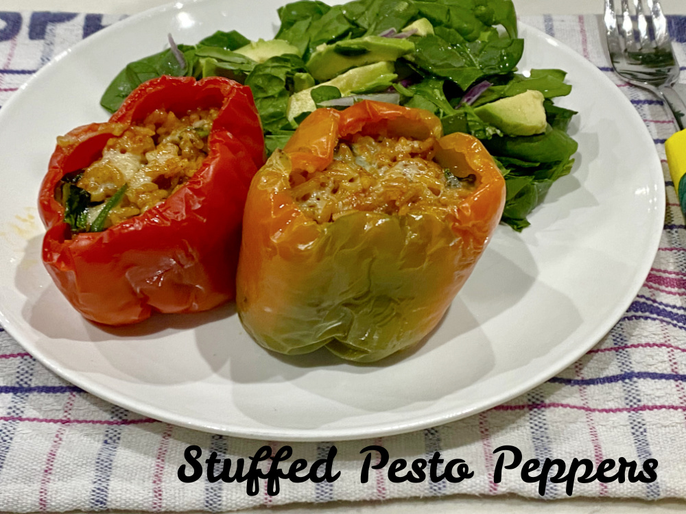 two stuffed peppers on a plate with green salad