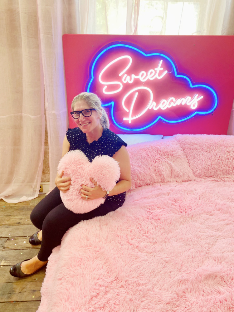 woman sitting on a bed hugging a heart pillow