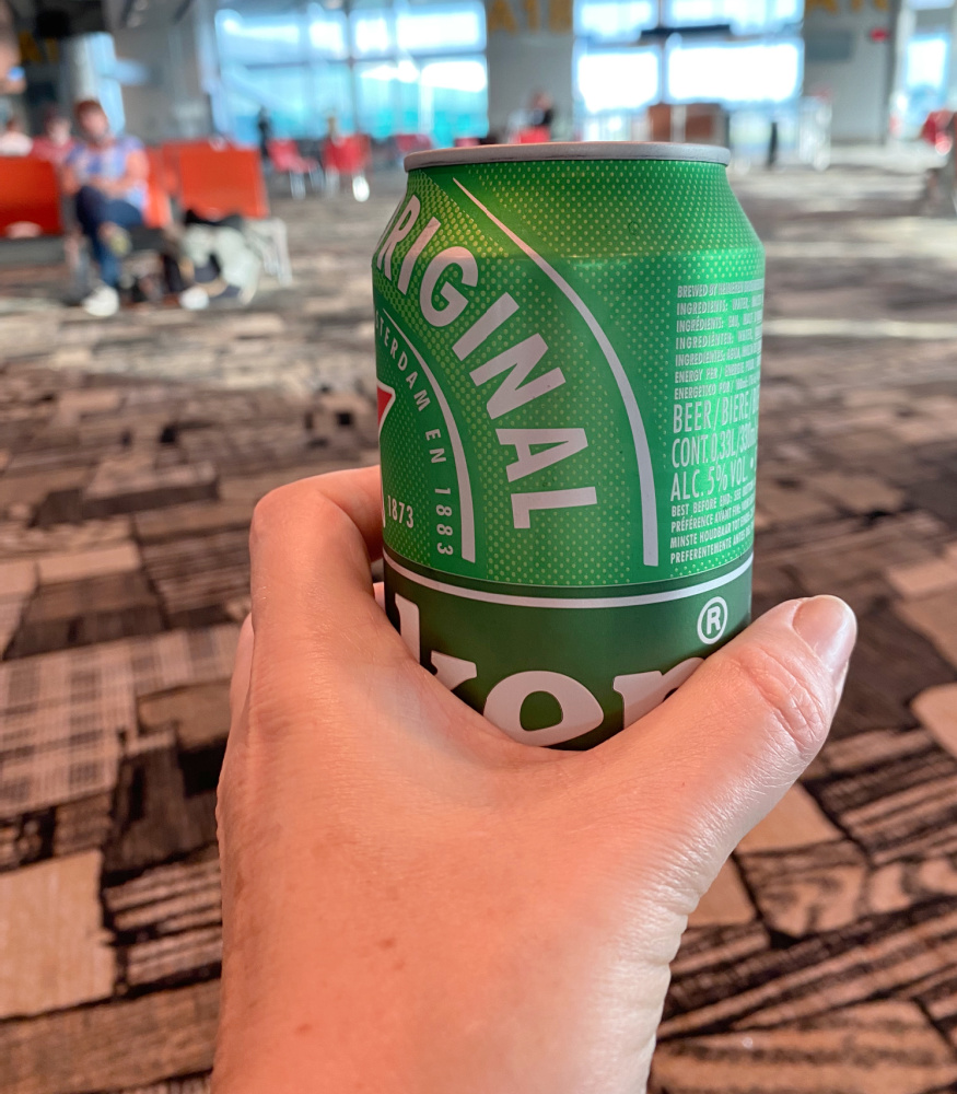 hand holding a can of beer at airport gate