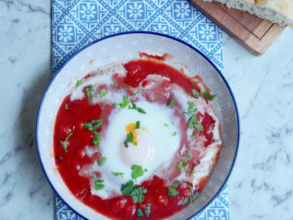 a bowl of shakshuka eggs with turkish bread on side