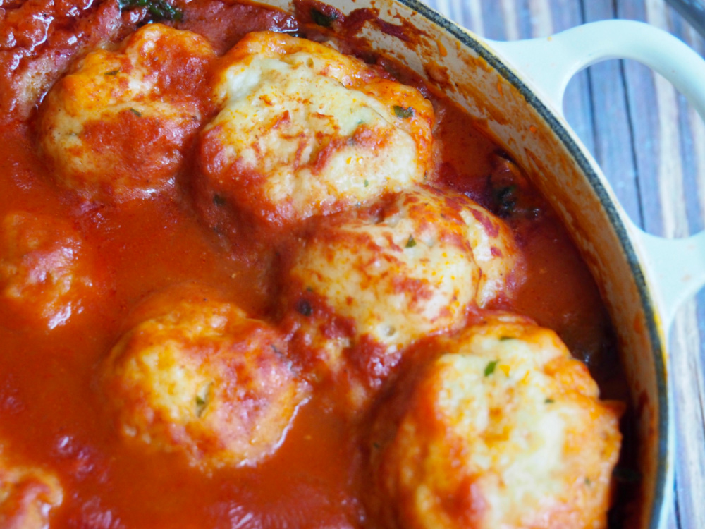 close up of chive dumplings in chicken and paprika stew