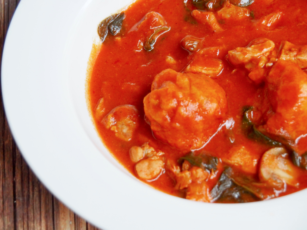 side view of plate of chive dumplings in chicken and paprika stew