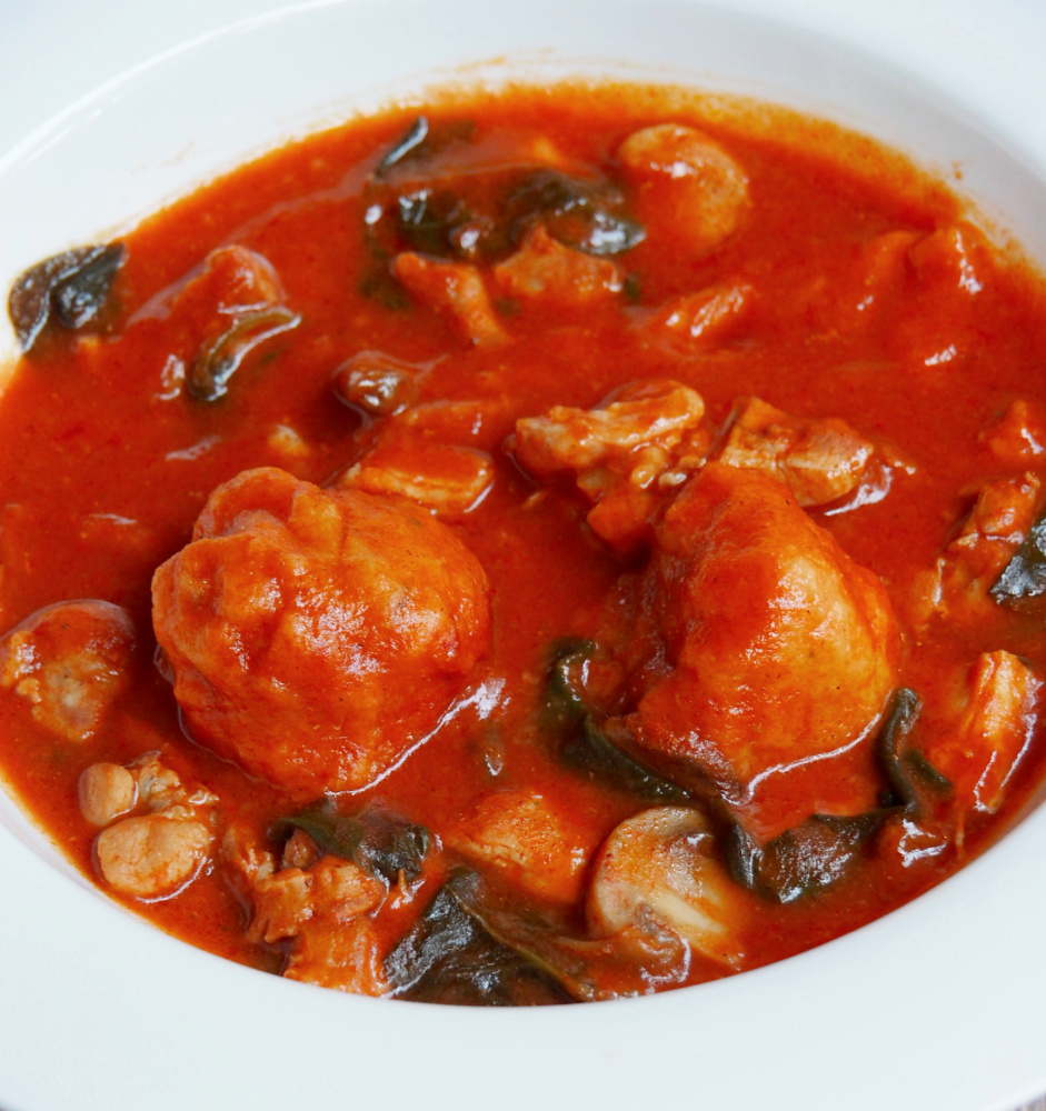 side plate of pot of paprika chicken stew with chive dumplings