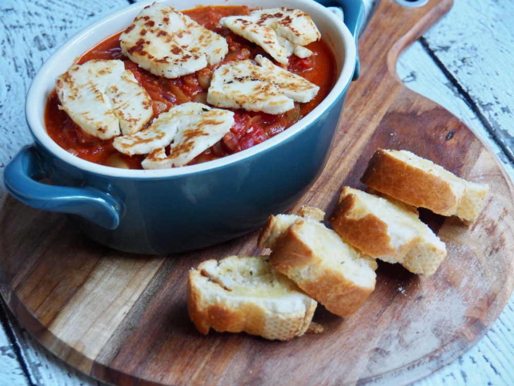 pot of halloumi and bean stew with garlic bread on round wooden board