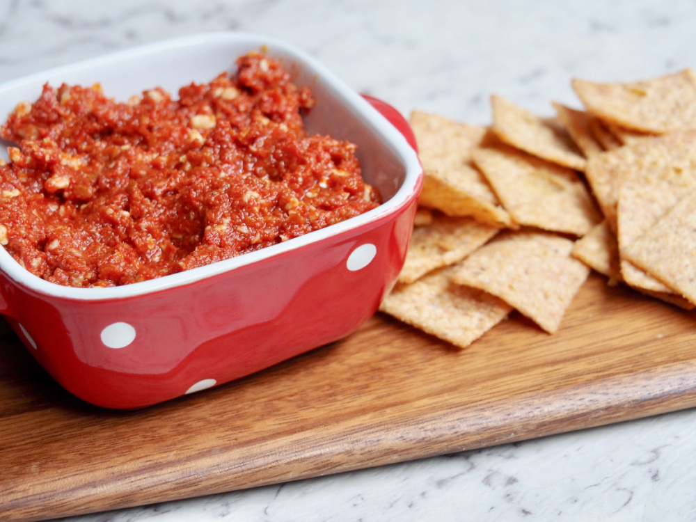 pot of vegan sundried tomato pesto on a board with crackers