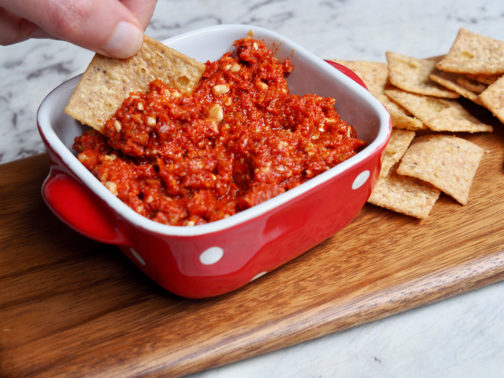 dipping cracker into sundried tomato pesto