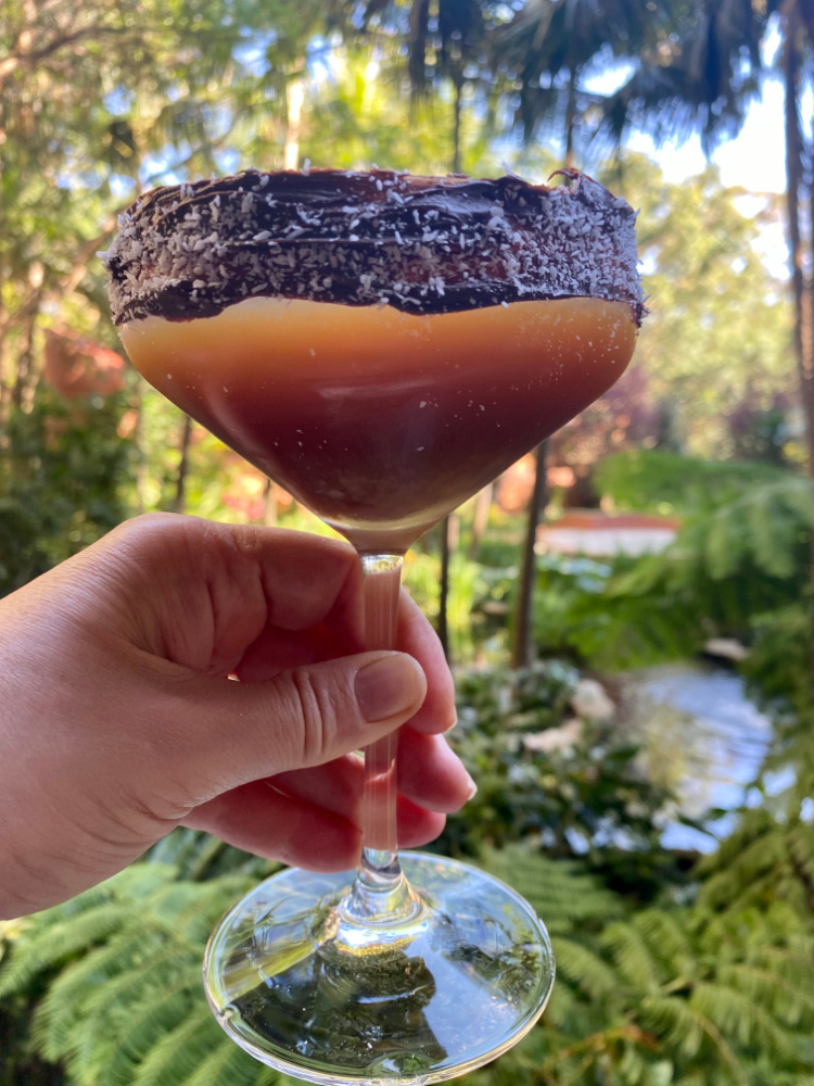 caramel coloured espresso martini in a glass decorated with chocolate and coconut around rim