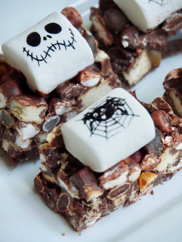halloween rocky road topped with large white marshmallows decorated with spiders and skull faces