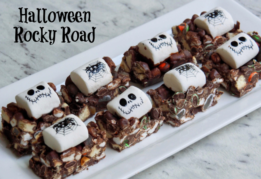 chocolate rocky road on rectangular plate topped with white marshmallows decorated with skull and spider faces