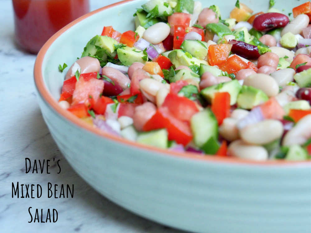 light green shallow bowl filled with chopped salad tomatoes cucumbers red onion and avocado