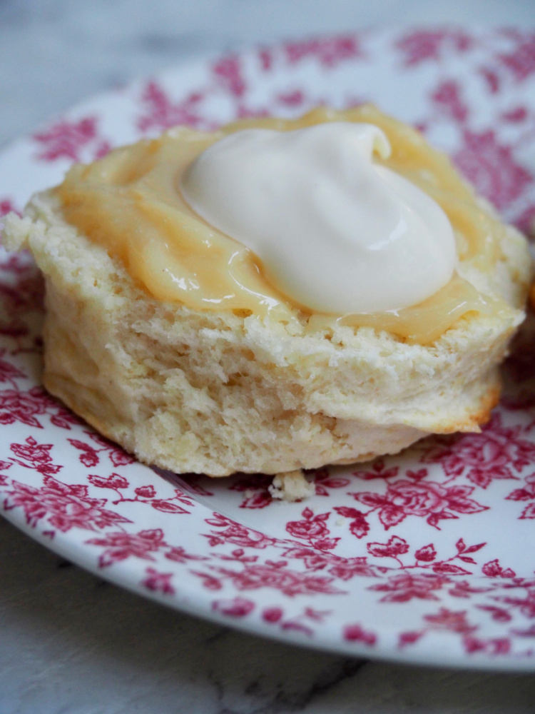 half a scone spread with lemon butter and cream