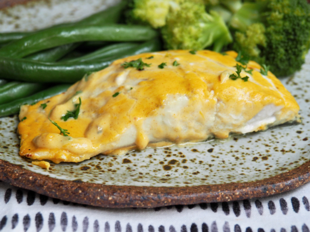 fish fillet baked in orange and mustard sauce with green beans and broccoli on plate