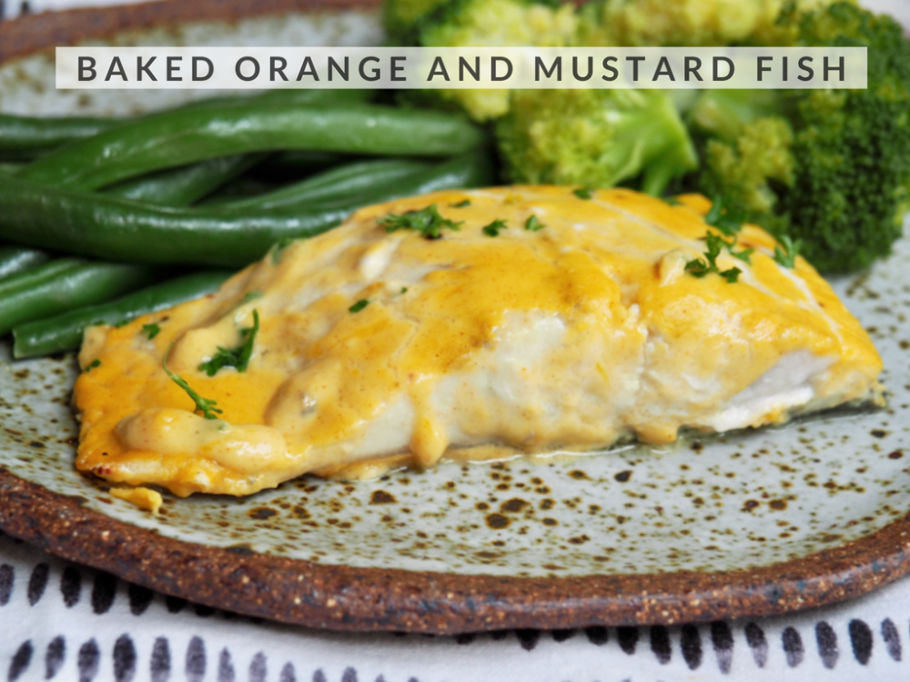 fish fillet in orange and mustard sauce with green beans and broccoli in the background