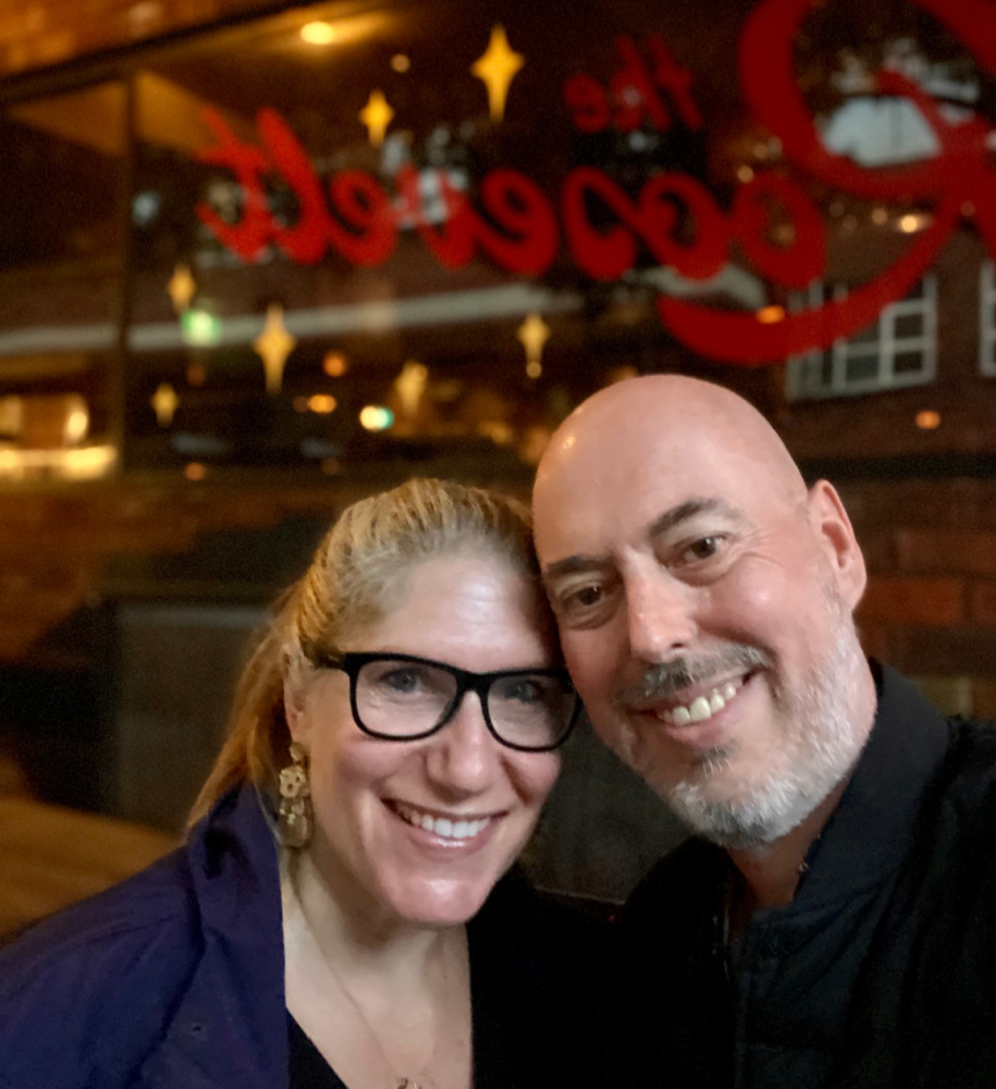 A man and a woman standing in front of a window with the word Roosevelt written in red script