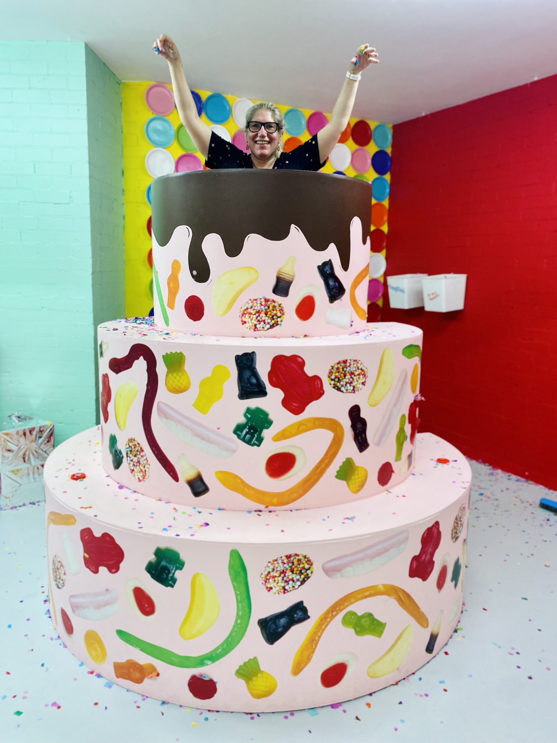 woman jumping out of model life size birthday cake throwing confetti