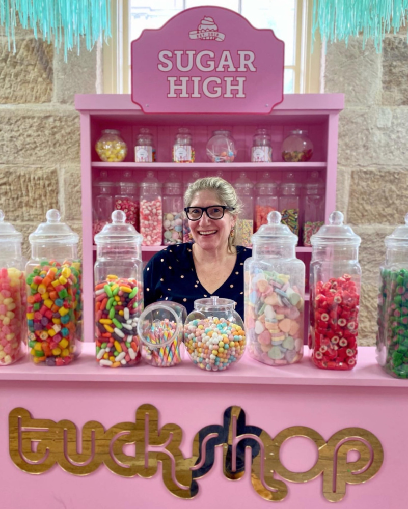 woman standing behind pink counter with large jars of candy