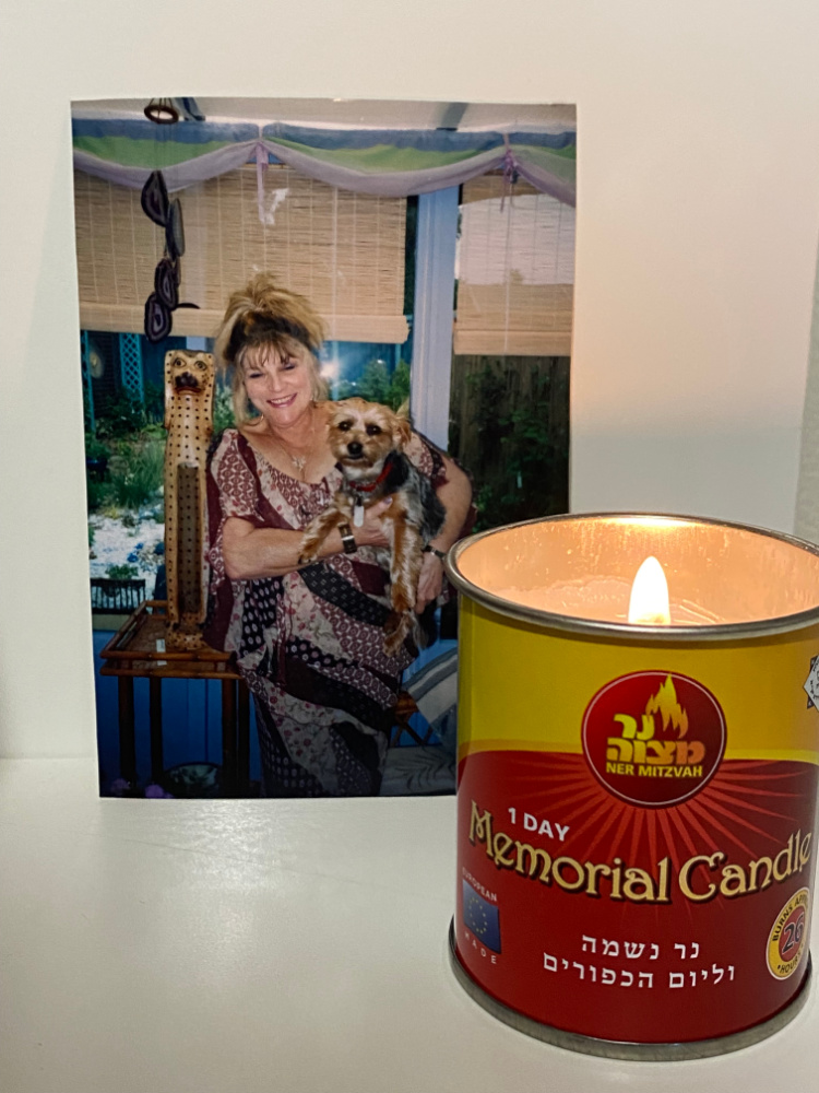 memorial candle in front of a photo of a woman smiling holding a dog