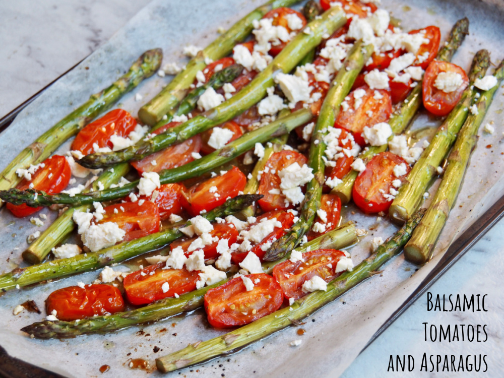 baking sheet lined with baking paper and topped with roasted asparagus spears halved cherry tomatoes and topped with crumbled feta