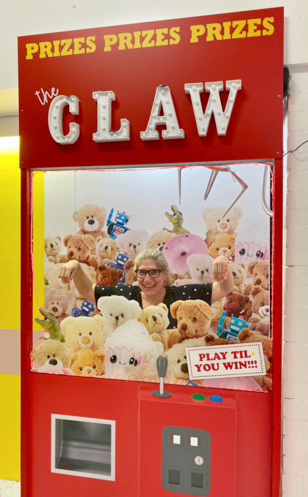woman standing amongst soft toys in claw machine