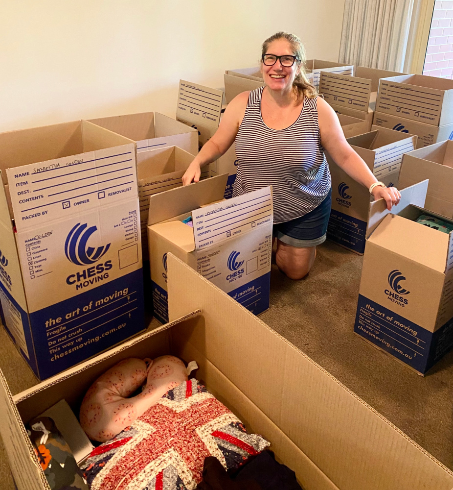 woman sitting in amongst a pile of packing boxes