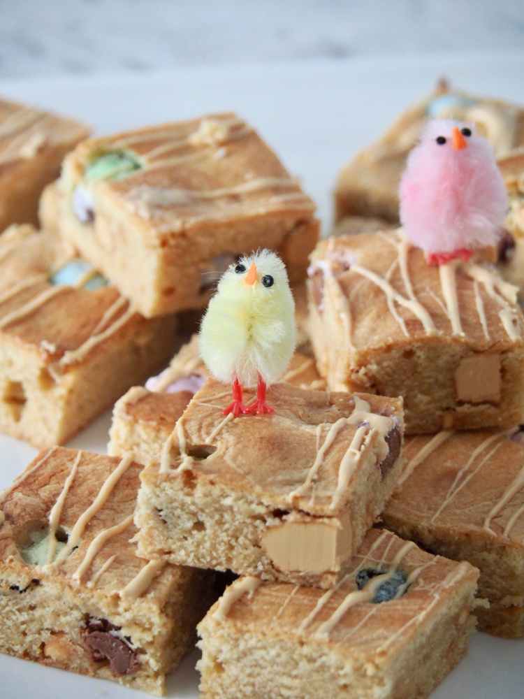 easter caramilk blondies stacked on plate with decorative chick on top